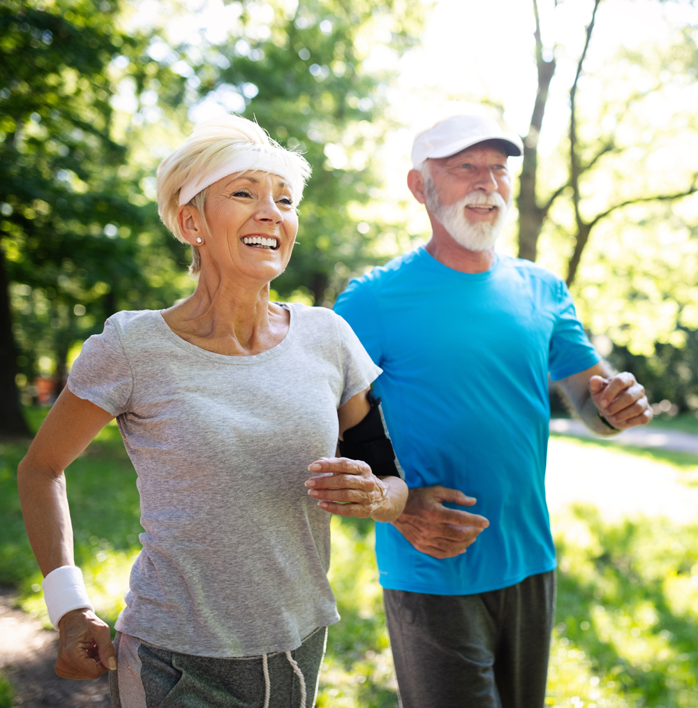 senior couple running on a path through nature