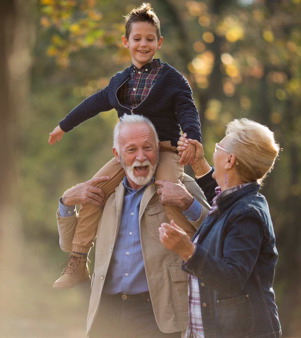 grandson sitting atop grandpas shoulder laughing with grandma