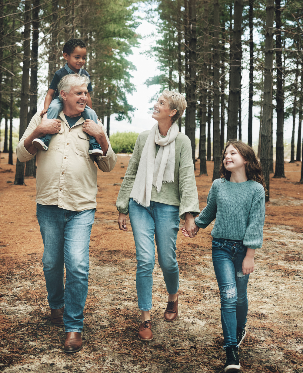 grandparents walking through the woods with their grandkids smiling and laughing together