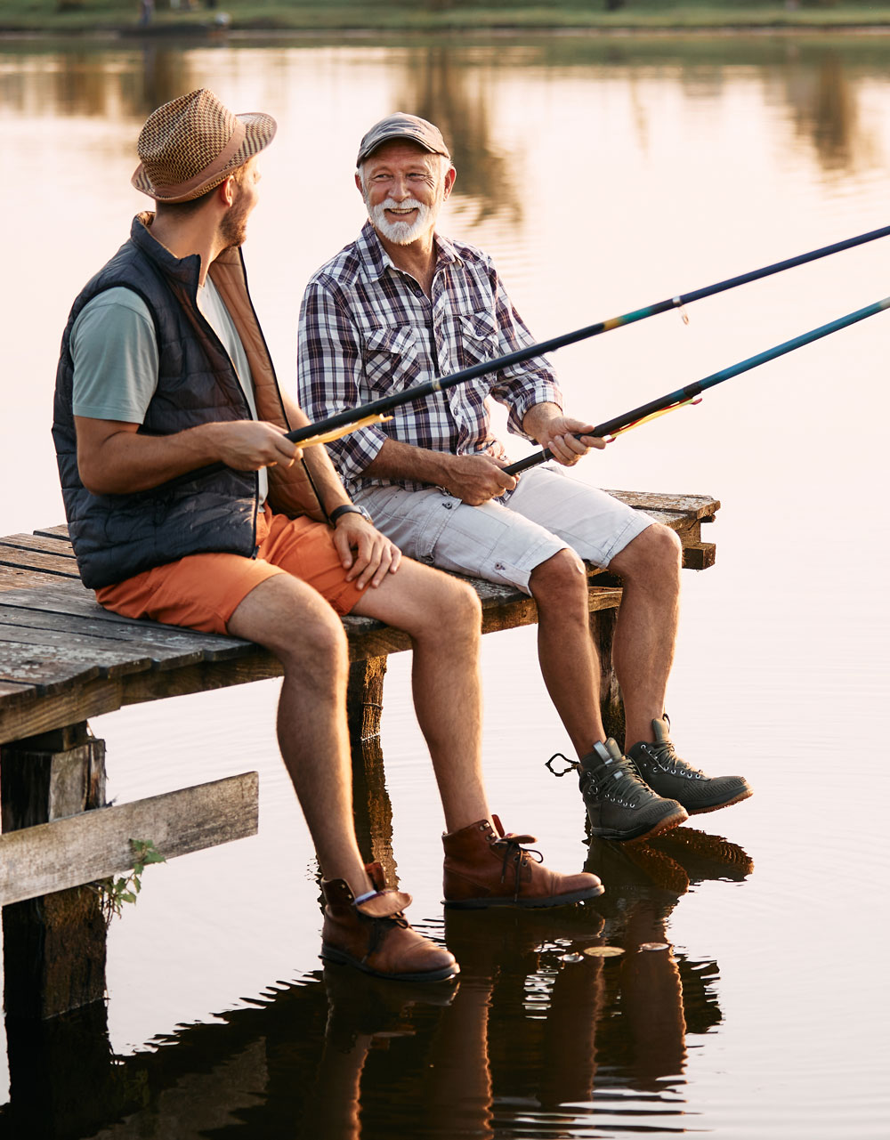 senior man and his son talk while fishing from dock