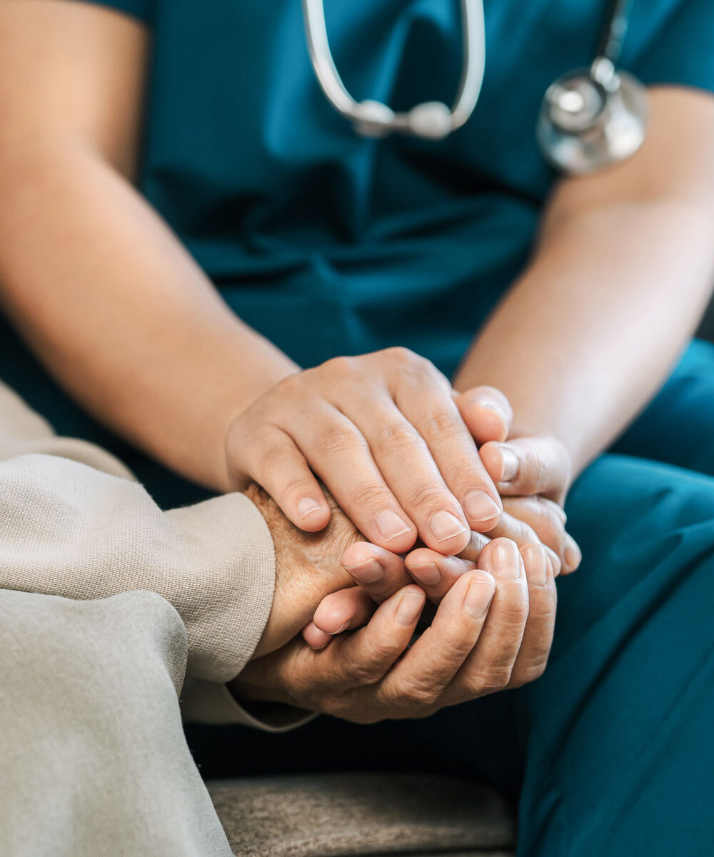 nurse caregiver holds hands to encourage and comfort an elderly woman