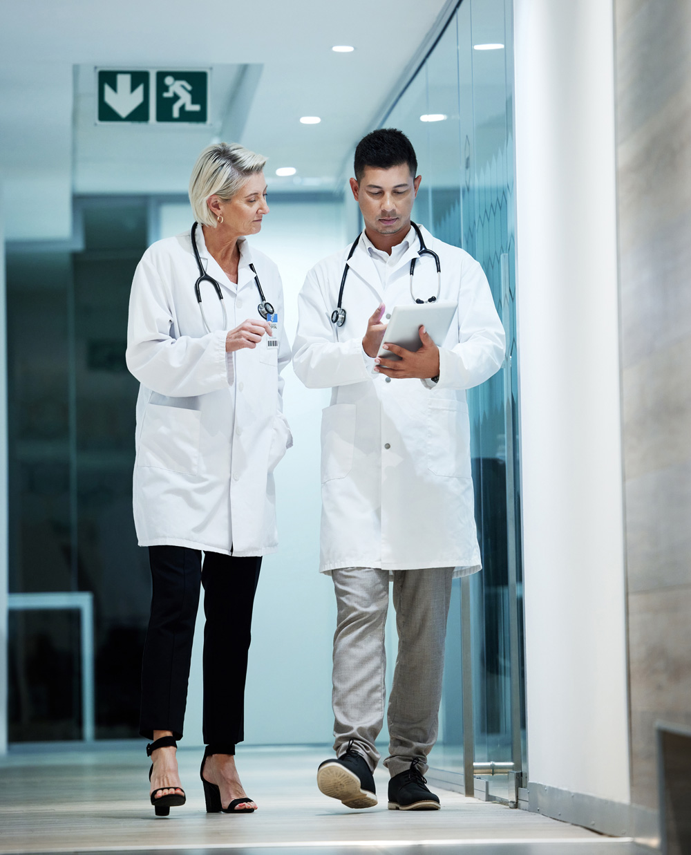 healthcare professionals in white lab coats walking through hospital hallway