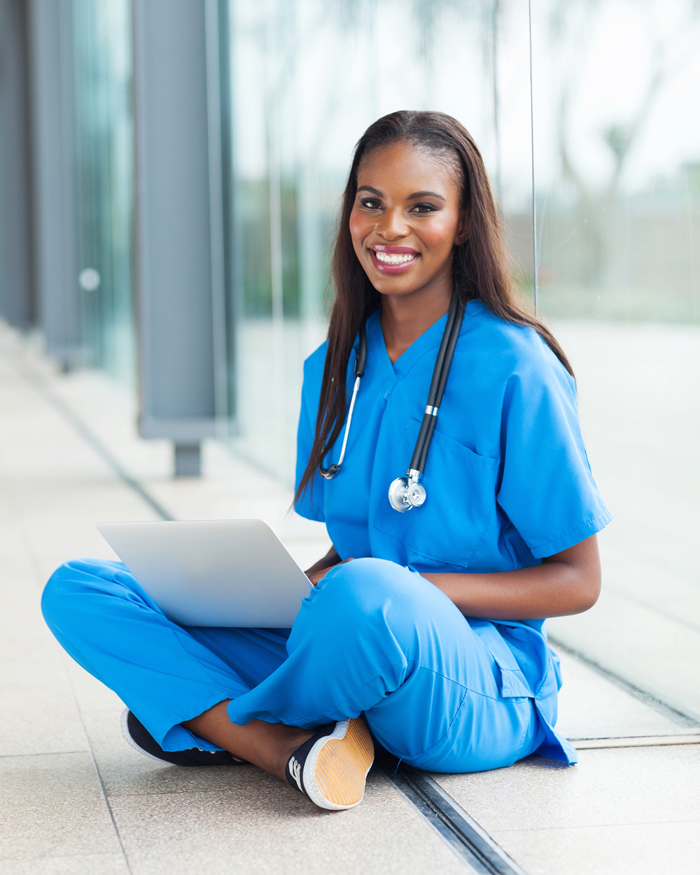 healthcare student studying with her laptop on a hospital hallway floor