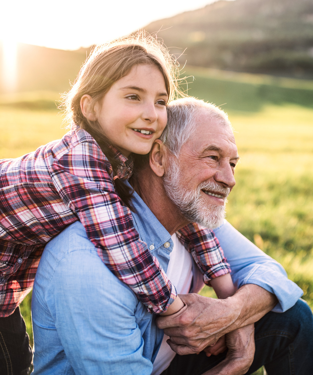 girl with grandfather outside in spring nature, relaxing on the grass