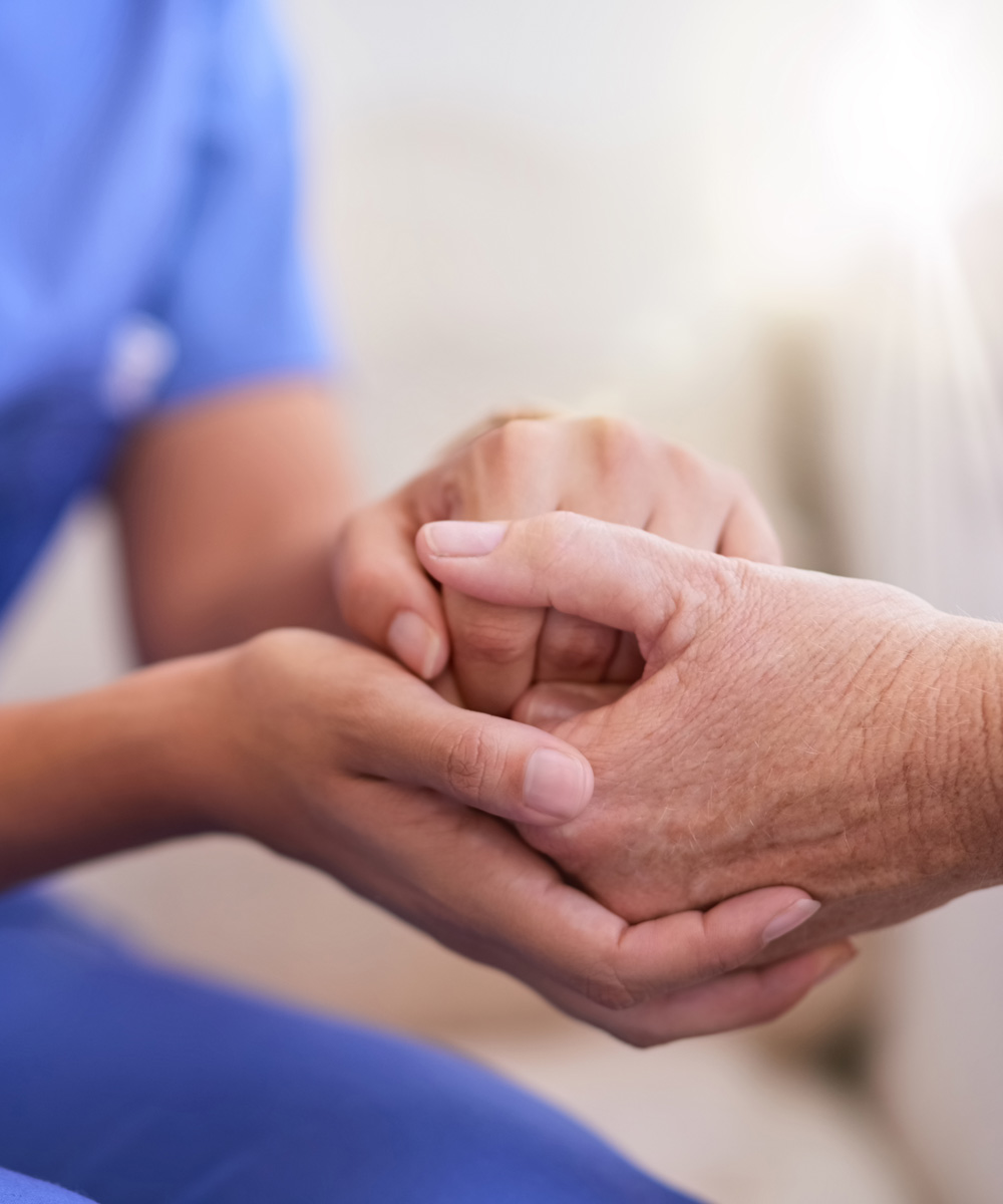 Nurse and senior woman holding hands