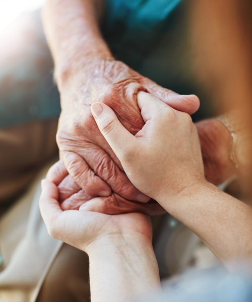 elderly hands holding younger hands of a nurse for comfort